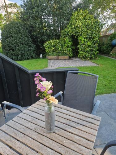 a vase of flowers on a wooden table with two chairs at Zeelucht Texel in De Koog