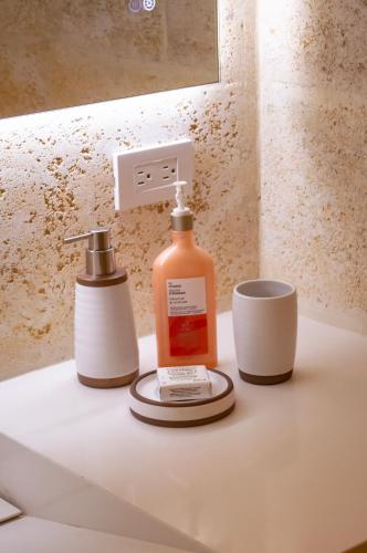 a bottle of soap and a cup on a bathroom sink at Macanao Lodge By LD in El Roque