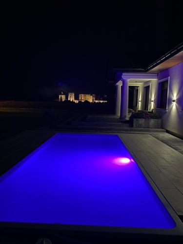 a blue swimming pool at night with a house at Dworek pod Krzyżtoporem Ujazd Agroturystyka- pokoje do wynajęcia in Iwaniska