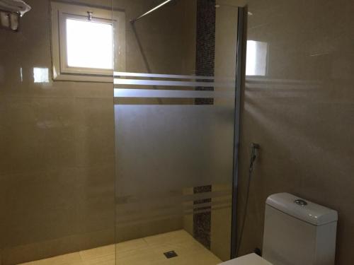 a bathroom with a shower with a toilet and a window at Asfar Plaza Hotel & Apartments in Riyadh