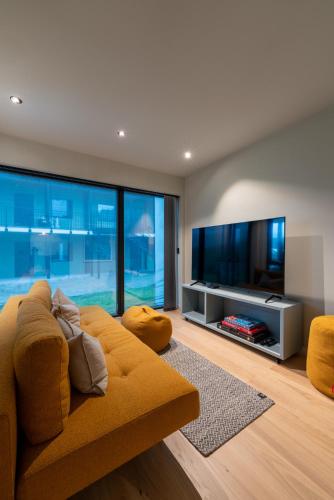 a living room with a yellow couch and a flat screen tv at Modern Apartment close to Leknes in Leknes