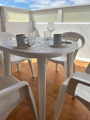 a white table with two chairs and two mugs on it at Garza Attic House in Ojos de Garza