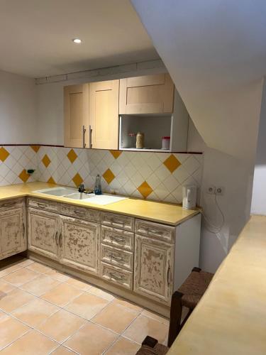 une cuisine avec des armoires en bois et un évier dans l'établissement Loft en pierres apparentes, à Coursan