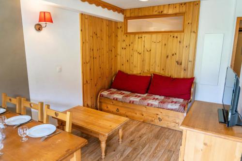 Cette chambre comprend une table et un lit avec des oreillers rouges. dans l'établissement Résidence Les Hauts De Preclaux - Appartement pour 6 personnes avec vue pistes MAE-9571, aux Orres