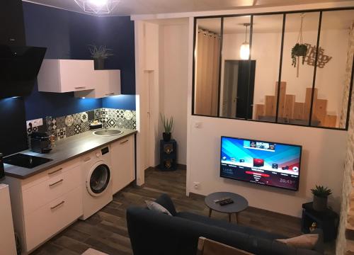 Il comprend un salon avec une cuisine et une télévision murale. dans l'établissement El Capullo - Appartement en Rdc avec cour en centre ville, à Châteauroux