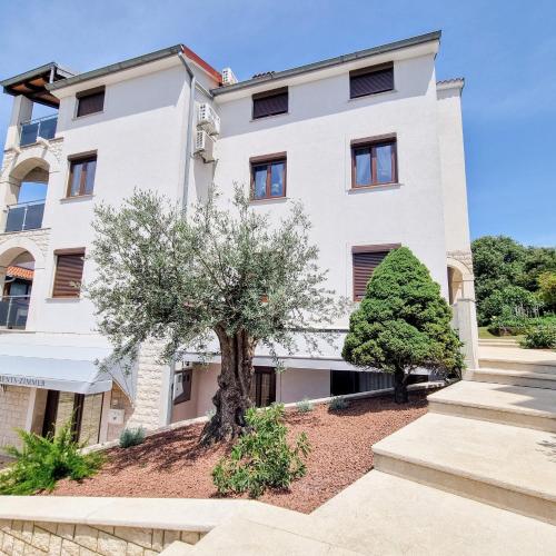a white building with a tree in front of it at Apartmani Senka in Vrsar