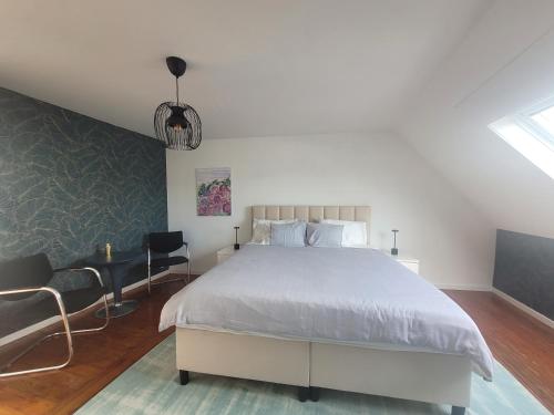a bedroom with a large white bed and a chair at Duplex Apartment in Varsenare