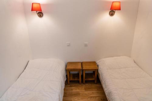 - 2 lits dans une chambre avec une table et des lumières dans l'établissement Résidence Les Hauts De Preclaux - Studio vue pistes au coeur des Orres 1800 MAE-0451, aux Orres