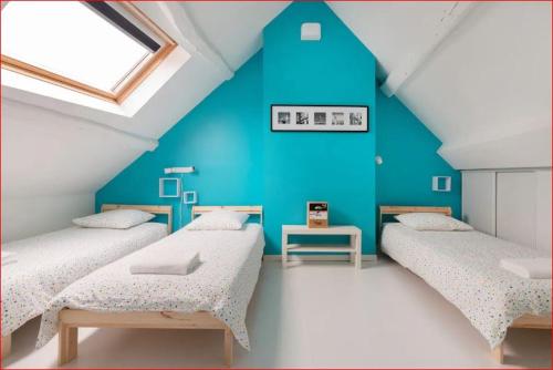 - 3 lits dans une chambre avec un mur bleu dans l'établissement Prolongez la magie aprés DisneyLand Paris, à Saint-Germain-sur-Morin