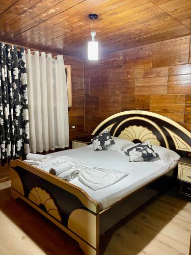 a large bed in a room with a wooden wall at Guest House DEA in Vlorë