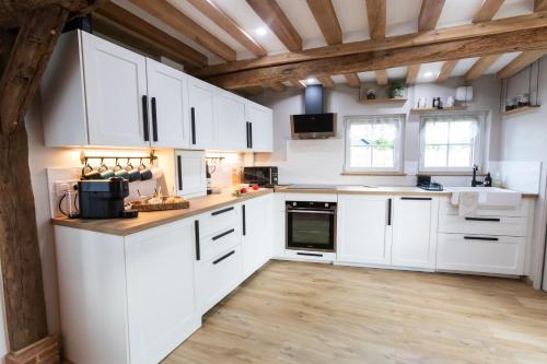 une cuisine avec des armoires blanches et un plancher en bois dans l'établissement Gîte Saint Amour, au Pin