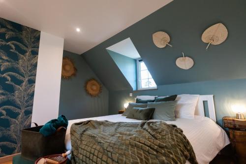 une chambre avec un grand lit aux murs bleus dans l'établissement Gîte Saint Amour, au Pin