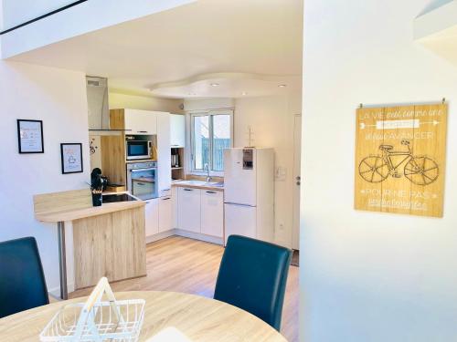 a kitchen with a table and a kitchen with a bike on the wall at Loft de charme avec parking, jardin et terrasse in Saint-Pryvé-Saint-Mesmin