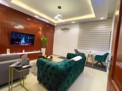 a living room with a green couch and a tv at Luxe à Fidjrosse in Cadjèhoun