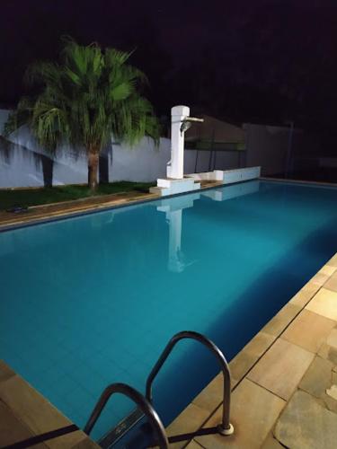 a swimming pool at night with a chair next to it at Hotel Arbom in Mogi Guaçu