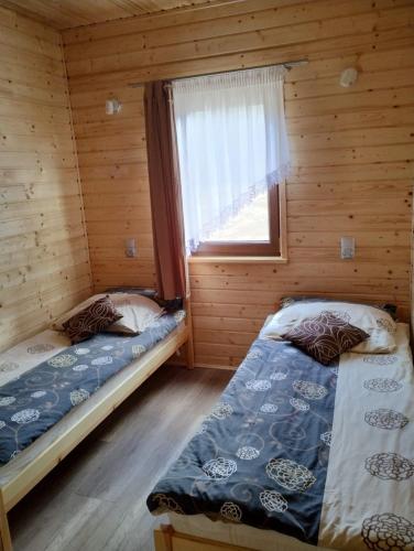 two beds in a log cabin with a window at Domki letniskowe OSTROWITE in Ostrowite