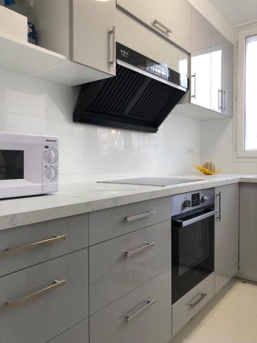 Il comprend une cuisine blanche équipée d'un four micro-ondes et d'une cuisinière. dans l'établissement Creteil new 1, à Créteil