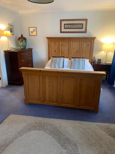 a bedroom with a large wooden bed with two pillows at Beautiful private room with Kingsize bed and large private en-suite in Peterborough