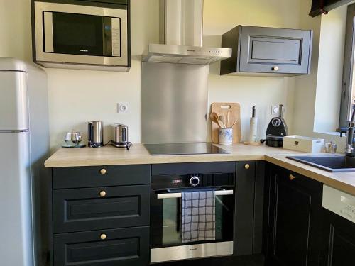 une cuisine avec des armoires noires et un four à plaques de cuisson dans l'établissement Appartement Belle-vue, à Liginiac
