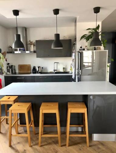 une cuisine avec un comptoir blanc et des tabourets en bois dans l'établissement Appartement 2 chambres-garage Lyon Montchat, à Lyon