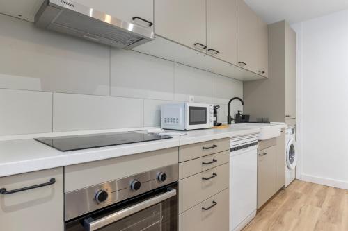 a kitchen with white cabinets and a microwave at Picasso, para 6 personas, espacioso piso de diseño in Gijón