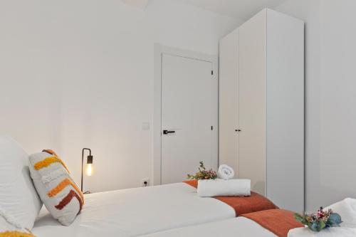 a white bedroom with two beds and a mirror at Picasso, para 6 personas, espacioso piso de diseño in Gijón