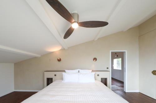 une chambre avec un lit blanc avec un ventilateur de plafond dans l'établissement Villa Helric dans Cassis - Jardin - Parking, à Cassis