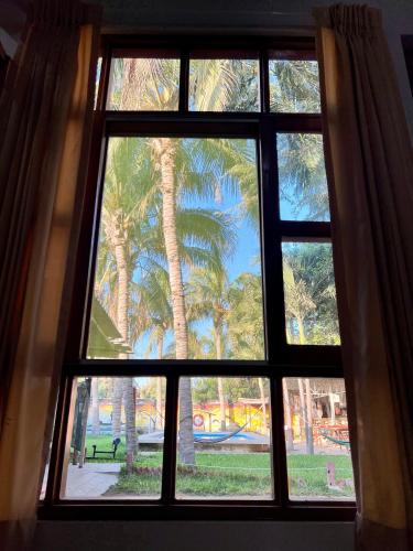 a window with a view of a palm tree at Stone House Mancora in Máncora