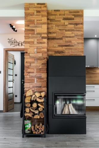 a fireplace in a living room with a pile of logs at Chaty ForRest in Valča