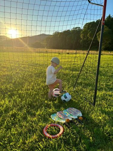a child sitting in the grass next to a soccer net at Chaty ForRest in Valča