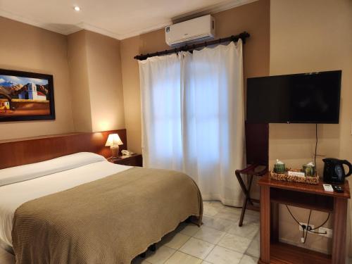a hotel room with a bed and a flat screen tv at Hotel Boutique La Candela in Salta