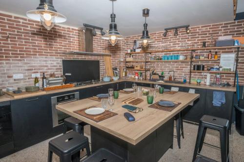 une cuisine avec une grande table en bois et un mur en briques dans l'établissement Le Domaine de Darvoy, à Darvoy