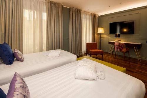 a hotel room with two beds and a desk at Hotel Indigo Turin by IHG in Turin