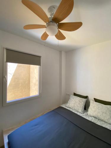 a bedroom with a ceiling fan and a window at Santa Banana Apartment Alicante in Alicante
