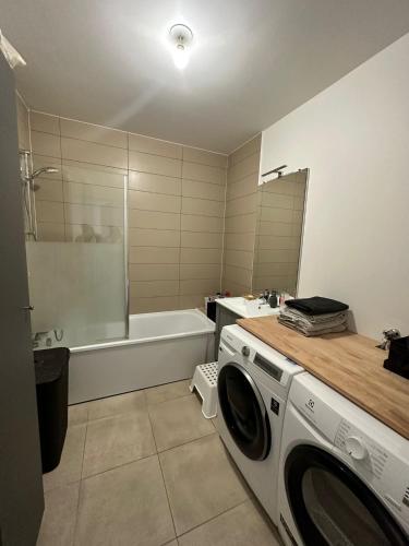 une salle de bain avec un lave-linge et une baignoire dans l'établissement Appartement Cosy proche Paris, à Arcueil