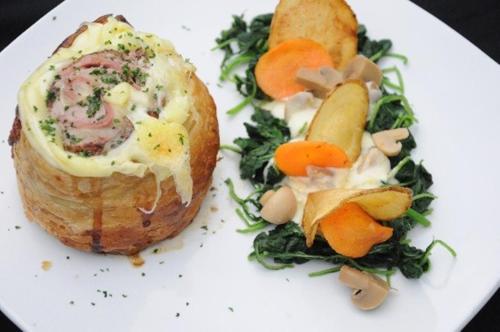 a white plate with a sandwich and vegetables on it at Grand Cakra Hotel Malang in Malang