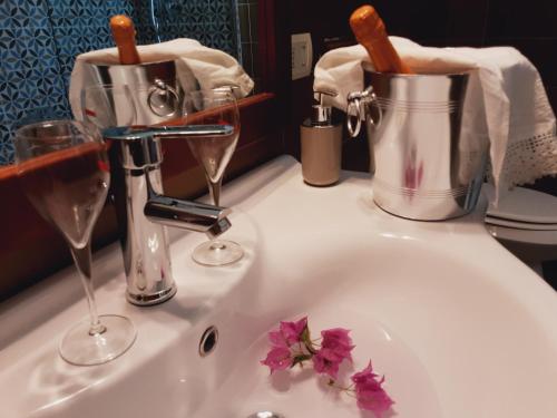 a bathroom sink with two glasses of wine and flowers at Relais LaValle in Taranto