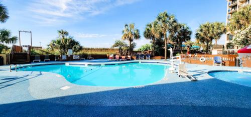 a large pool with blue water and palm trees at Luxury Ocean Front By Barefoot Landing in Myrtle Beach