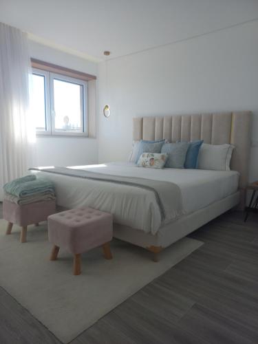 a white bedroom with a large bed and a window at Apartamento na praia in Póvoa de Varzim