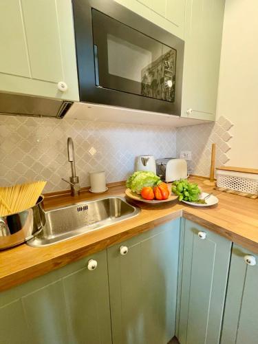 a kitchen counter with a sink and a plate of vegetables at Happy Family Apartments Maggiolino in Genova
