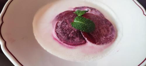 un dessert violet avec une feuille verte sur une assiette blanche dans l'établissement Château Saint-Martin, à Carcassonne