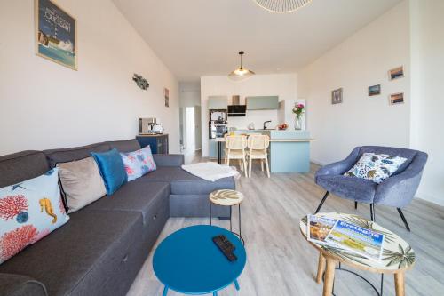 un salon avec un canapé gris et un fauteuil bleu dans l'établissement AR RANNDI - Splendide T3 de standing vue mer, à Porspoder