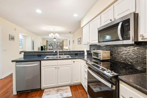 a kitchen with white cabinets and a sink and a microwave at 17C Fairway 17 Waterside at True Blue condo by Peace Vacations in Pawleys Island