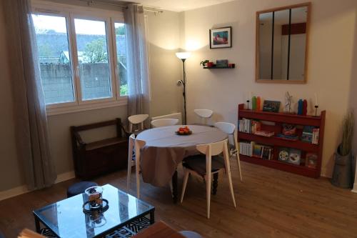 un salon avec une table et des chaises et une fenêtre dans l'établissement Appartement avec jardin au coeur de Rennes, à Rennes