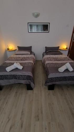two beds in a room with wooden floors at Odisea House in Ljubaništa