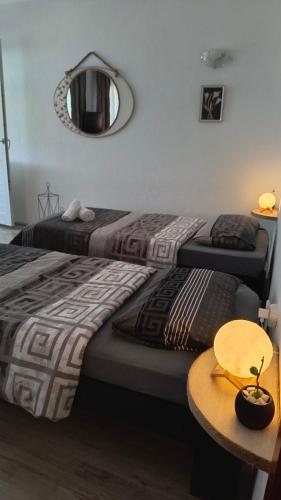 two beds in a room with a table and a mirror at Odisea House in Ljubaništa