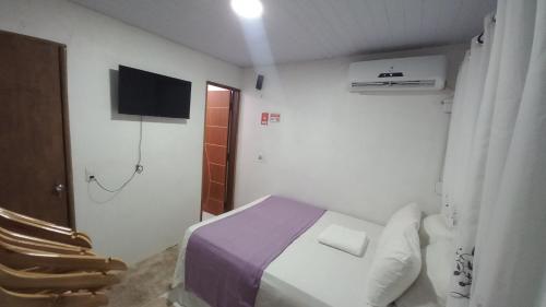 a small room with a bed and a television at Vila dos Bangalôs in Barreirinhas