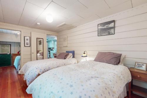 two beds in a bedroom with white walls and wood floors at Walk to Town! Dog-Friendly Quincy Getaway w/ Deck in Quincy