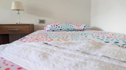 a bed with a colorful comforter and a pillow at Villa Paradise - Mar y Naturaleza in Punta de Piedra
