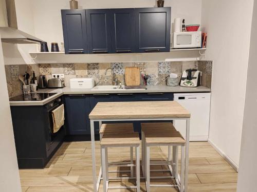 une cuisine avec des placards bleus, une table et des tabourets dans l'établissement Spacieuse maison proche mer, à Lanvollon